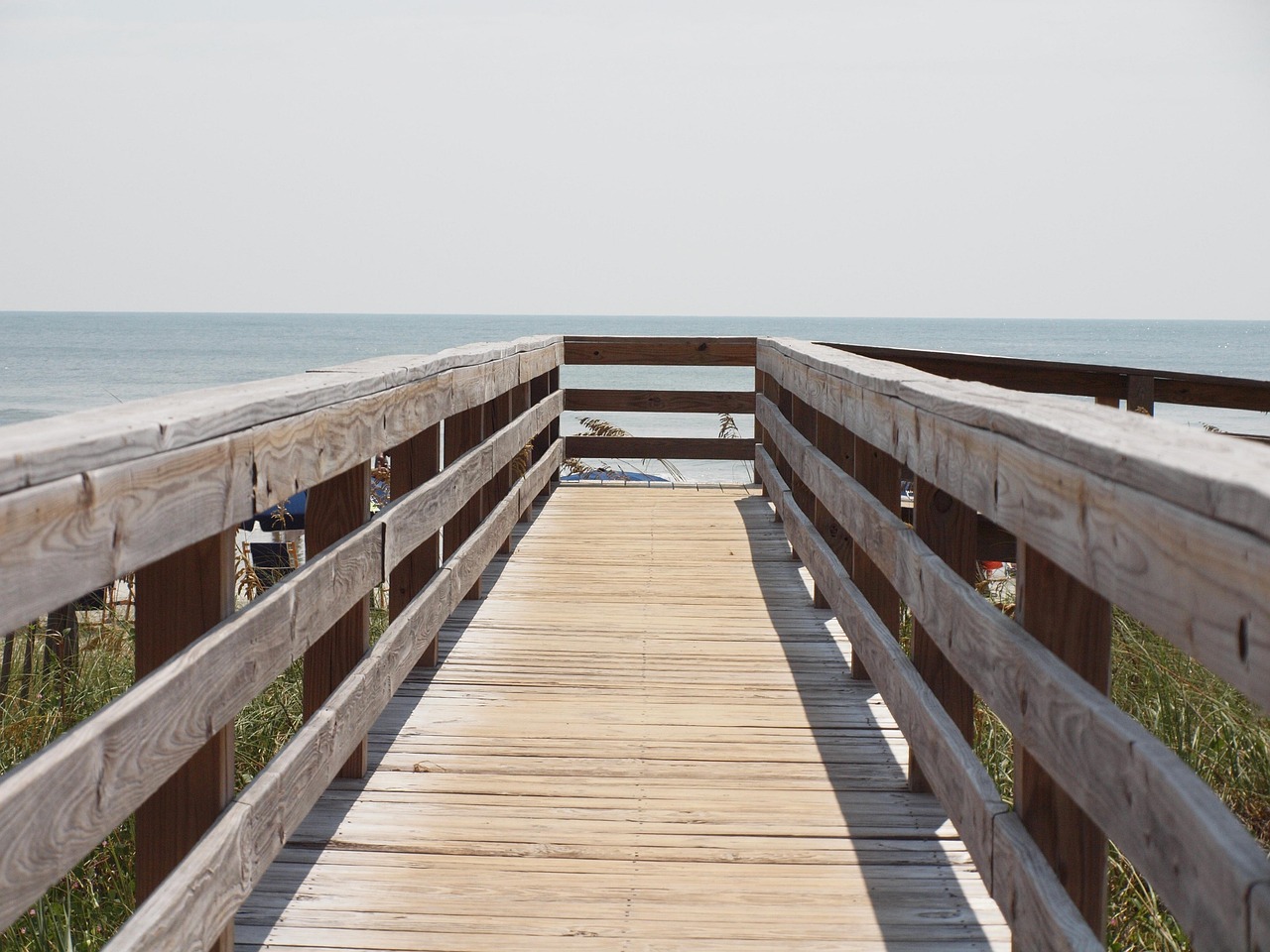 Coastal boardwalk stretching toward calm Australian waters at sunrise
